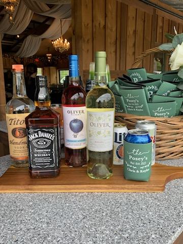 Wine and liquor bottles displayed with custom drink koozies