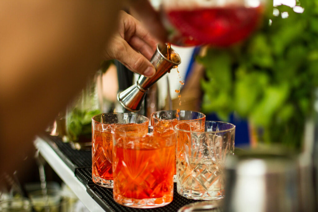 Bartender pouring bitters into orange cocktails over ice