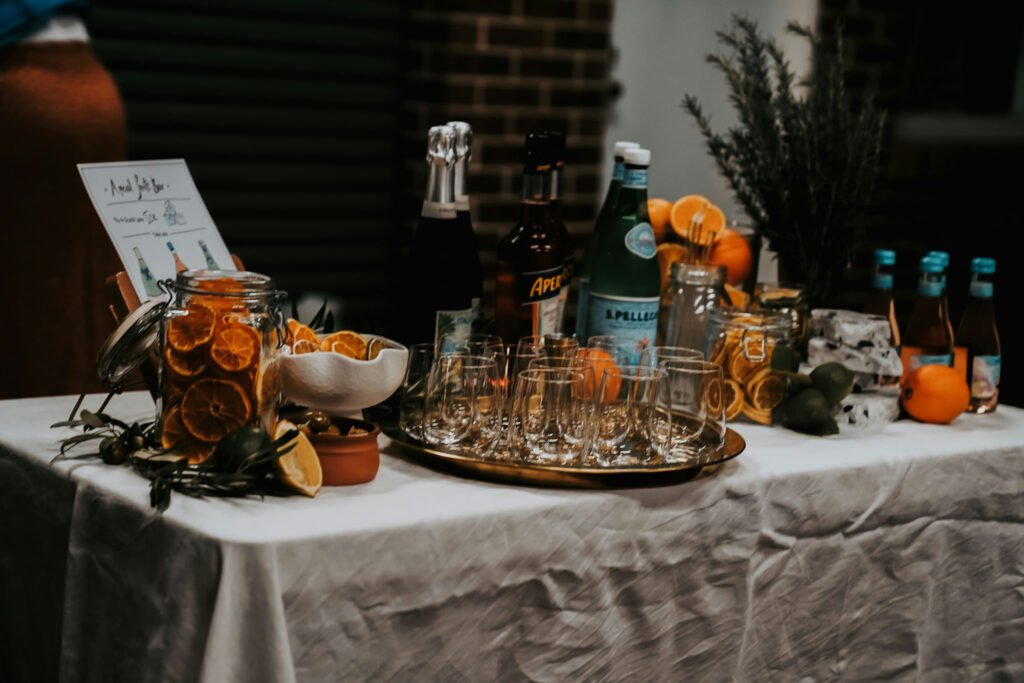 Liquor catering station with glassware, citrus garnishes, and bottled mixers