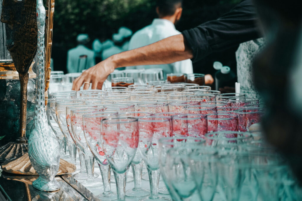 Bartender arranging rows of glasses at an outdoor event